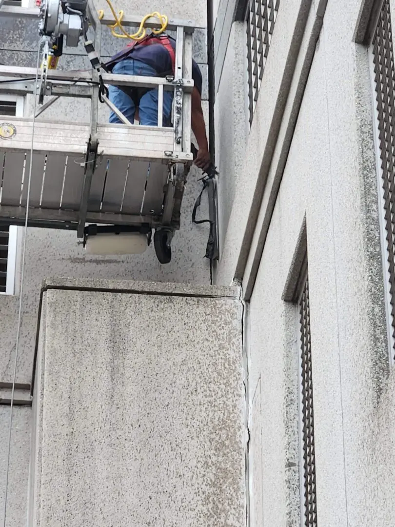 A man on a crane working on the side of a building.